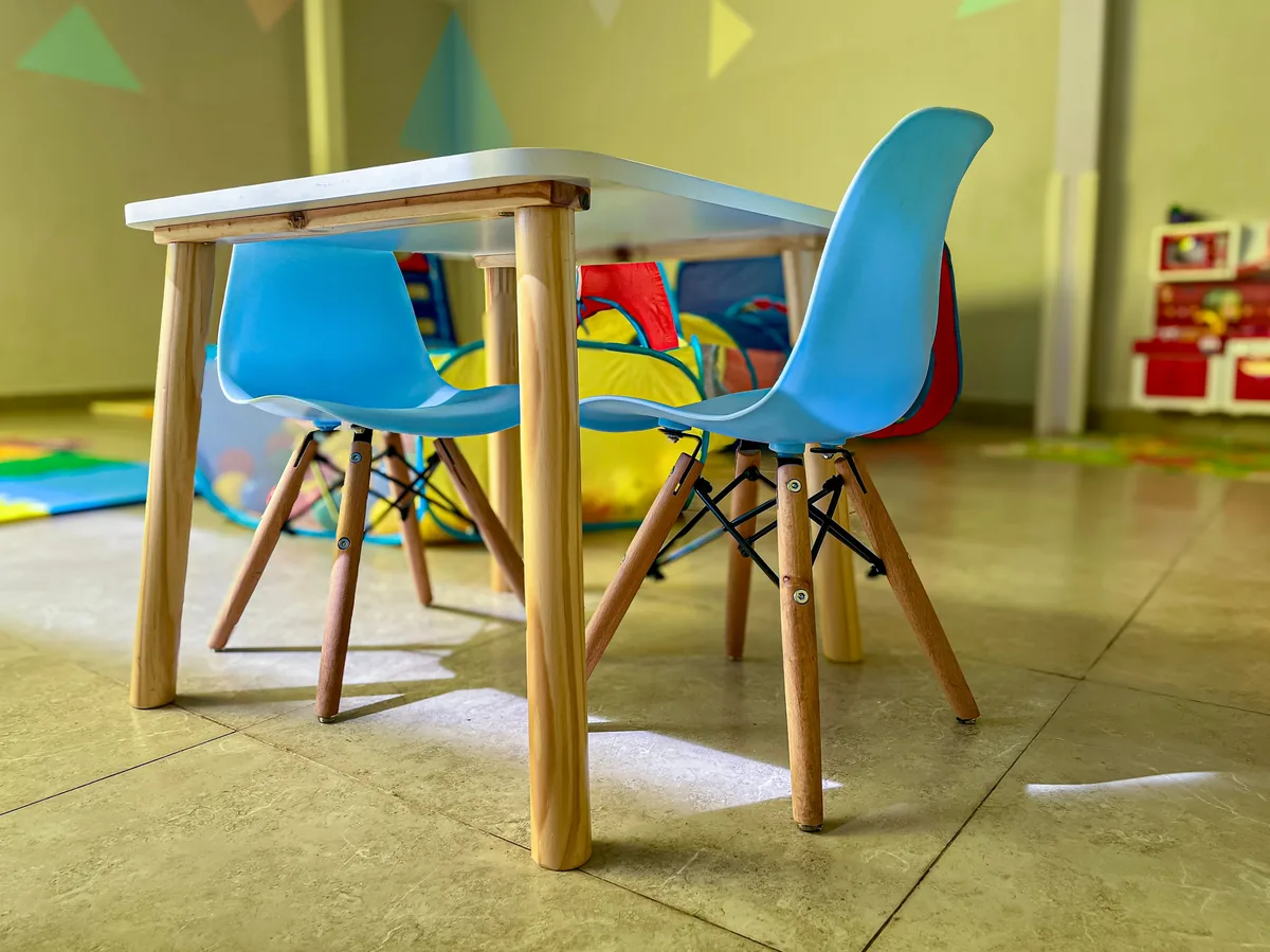 Playroom de guardería con mesa infantil y zona de juegos colorida